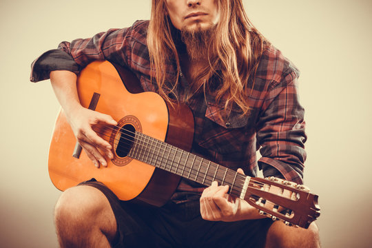 Sitting man playing guitar.