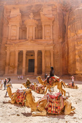 Petra, Jordan. Temple carved out of stone, camels, tourists.