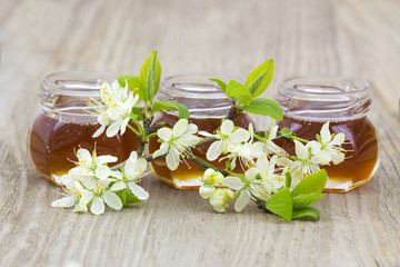 Obraz na płótnie Canvas Honey in jars and flowers on wooden background