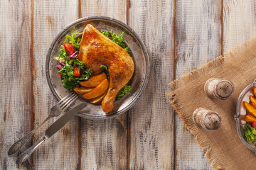 Baked chicken leg, served with roasted potatoes and vegetables.