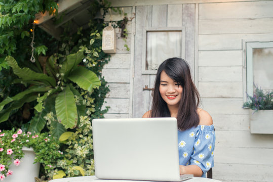 Portrait of a pretty young woman working on her computer on a terrace of her house