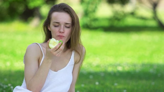 Young woman biting and eating tasty green apple
