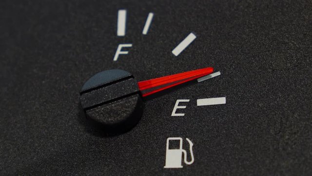 Close up shot of real dashboard and car fuel gauge quickly drops from full to empty. Not animation