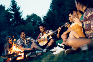 Friends enjoying music near campfire