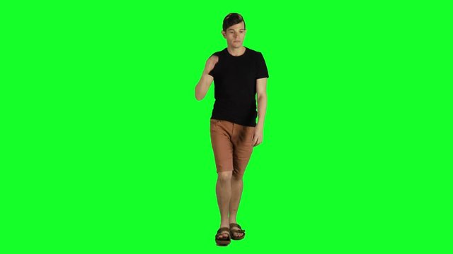 Young man in a full shot walking towards the camera over a green screen. Casual look,  Sad, stressed and ill, average speed.