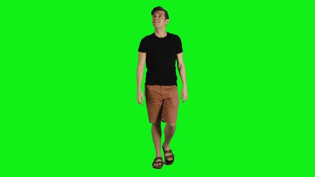 Young man in a full shot walking towards the camera over a green screen. Casual look, Smiling, looking up, average speed.