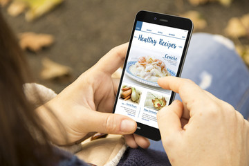 woman with healthy recipes phone in the park