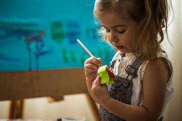 the little girl in the painting process, at the easel