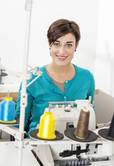 Happy Tailor Sitting At Workbench In Sewing Factory