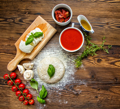 Pizza dough with tomato sauce on wooden table