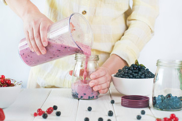 Close up of a female hands making a smoothie with fruits and ber