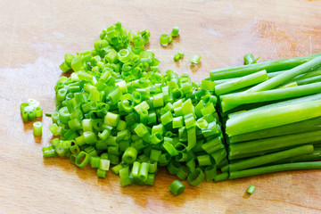 chopped green onions on an old wooden chopping board closeup