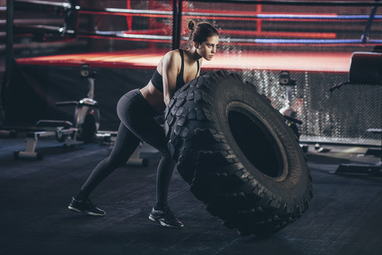 Female athlete exercising with tire at gym