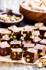 Dark  chocolate cubes with pistachios on wooden background