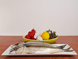 Fresh mackerel on a plate and fresh ingredients.