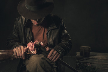 Cowboy looking at pink roses in rifle over gray background