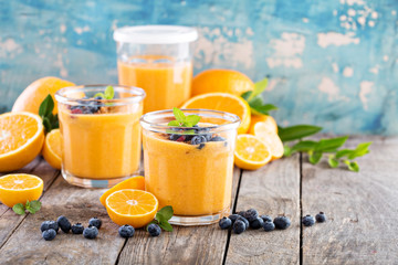 Orange and mango smoothie with granola and berries