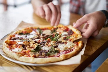 Tuinposter Pizzeria etenstijd bij pizzeria, man die een stuk pizza neemt