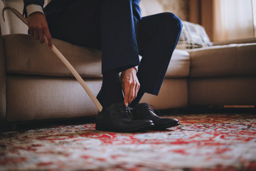 Men wearing work black boot. sitting on the couch in a blue suit