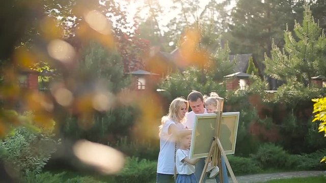 Young family painting on an easel in the garden.
