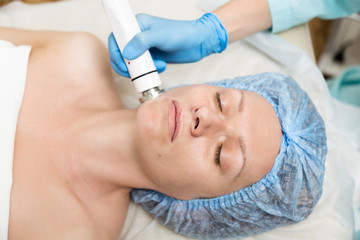 Obraz na płótnie Canvas Beautician makes RF-lifting to young woman. The cosmetic procedures for the face. Beauty treatments in the spa salon. Facial Skin Care