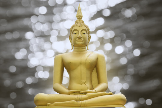 Gold image of Buddha on blurred light bokeh background,filtered image