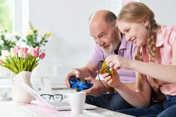 Obraz na płótnie Canvas grandfather and granddaughter playing video games