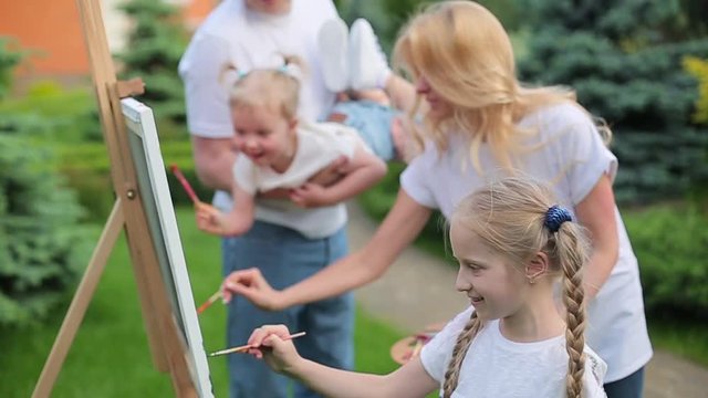 Little girls draw paints with family.