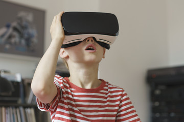 Boy wearing virtual reality simulator at home