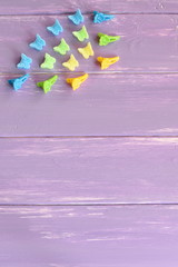Bright hair clips with flowers and butterflies. Kit of colorful hair clips for girls on lilac wooden background with copy space for text. Vertical photo. Top view