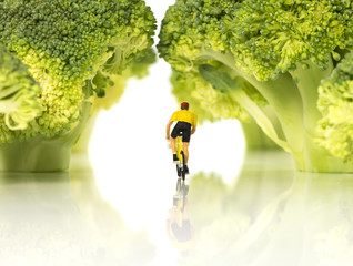 miniature figure man on bike in green swaeater on tour de france in green forest