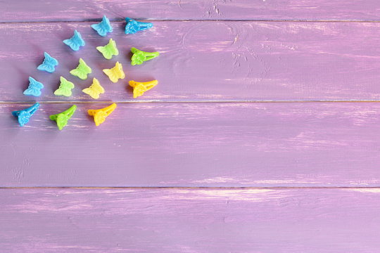 Assortment of plastic hair clips for girls. Blue, yellow, green hair clips on lilac wooden background with empty space for text. Girl bright summer hair accessories. Top view