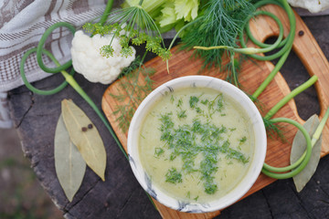 Bowl of green cream soup on wooden table