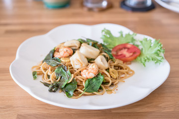 spicy spaghetti seafood with chicken on wood table. Thai style