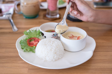 woman eating boiled rice with steamed eggs  on wood table