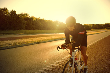 Obraz premium Light flares from sun over man training on bike