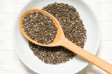Chia seeds in a wooden spoon on white background