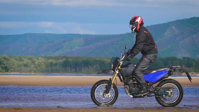 The feeling of freedom and Moto aesthetics. Motorcyclist riding on his bike on sandy beach.