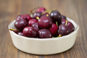 cherries in dish on dark brown wooden background