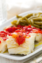 boiled cod fish with red pepper and green beans on white dish