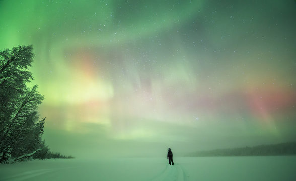 Person in snowscape with Aurora borealis, Finland