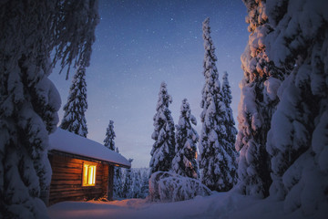 Cabin with light on at night in snow, Finland