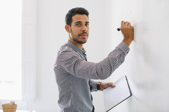 Man in office writing chart on wall