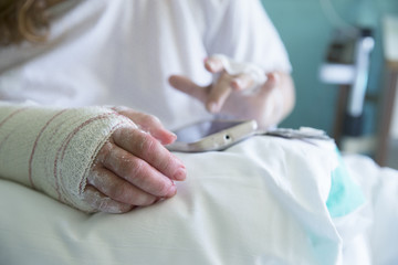 Woman in the hospital, operated hand, using mobile phone, left hand