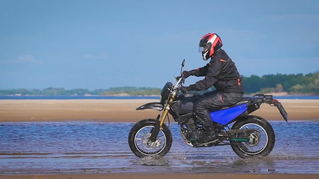Extreme driving a motorcycle. A skilled biker riding on the edge of water