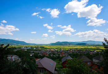 Country landscape in mountain valley with houses on blue sky