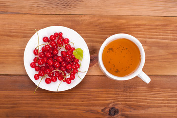 Cup of tea and currants on a wooden table. View from above .