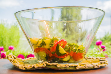 a big bowl of salad on the table in front of a green garden
