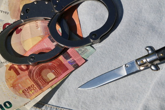 Springmesser mit Handschellen und Euroscheinen, kriminelle Delikte geschehen manchmal schon wegen kleinster Geldbetr&auml;ge
