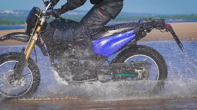 Extreme driving a motorcycle. A skilled biker riding on the edge of water